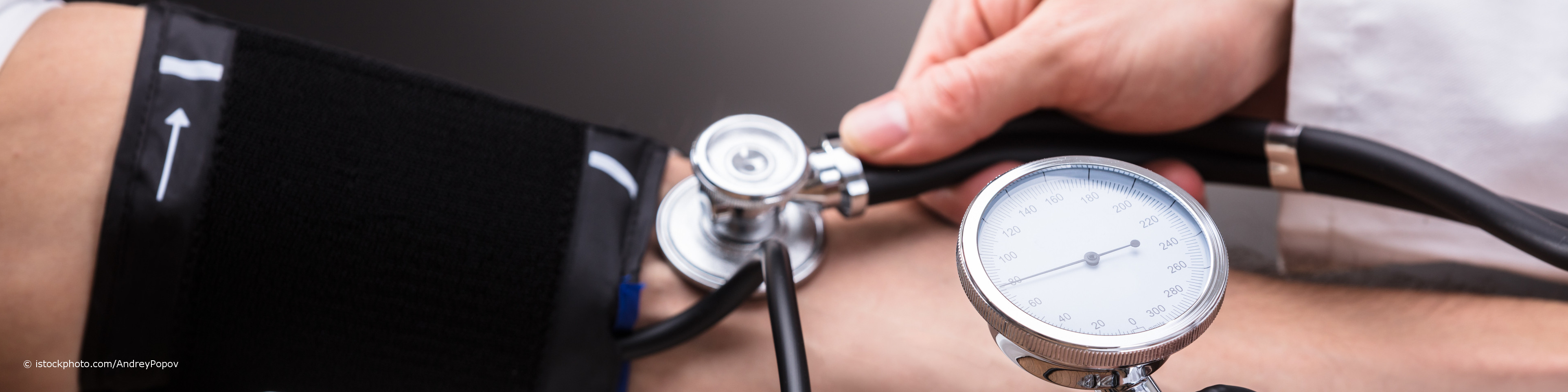 Bei docinsider registrierter Arzt misst den Blutdruck am Oberarm eines Patienten mit Bluthochdruck.